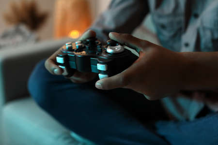 African-American teenage boy playing video game at home in evening, closeupの写真素材