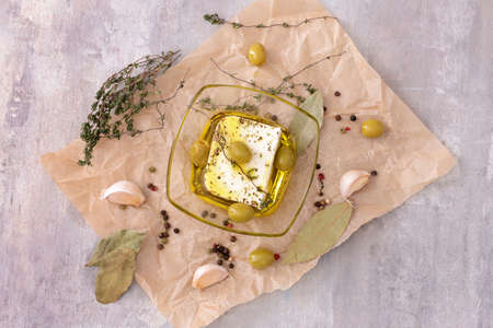 Tasty feta cheese with olives, oil and spices on gray backgroundの写真素材