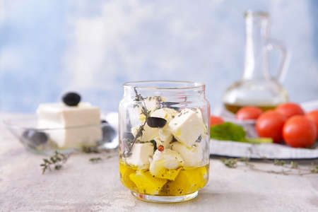 Jar with tasty feta cheese with olives, oil and spices on tableの写真素材