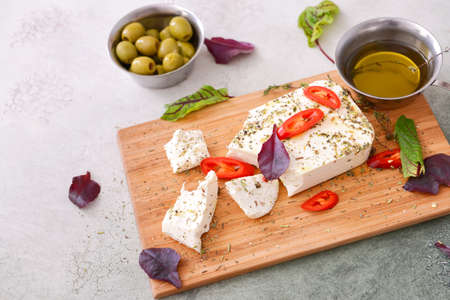 Tasty feta cheese with herbs, spices and oil on gray backgroundの写真素材