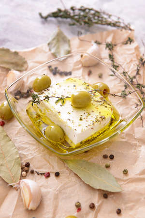 Tasty feta cheese with olives, oil and spices on tableの写真素材