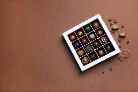 Box with delicious chocolate candies on color backgroundの写真素材