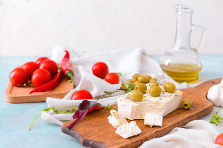 Board with tasty feta cheese, olives and spices on tableの写真素材