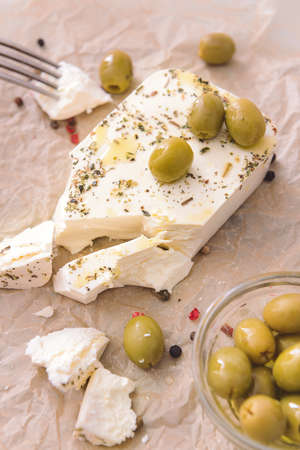 Tasty feta cheese with olives and spices on tableの写真素材