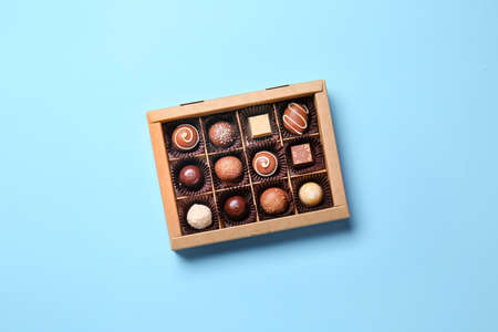 Box with delicious chocolate candies on color background