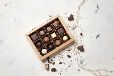 Box with delicious chocolate candies on light background
