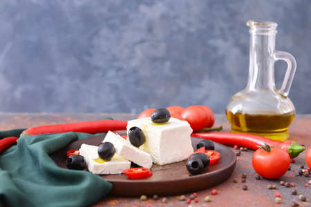 Tasty feta cheese with vegetables and spices on tableの写真素材