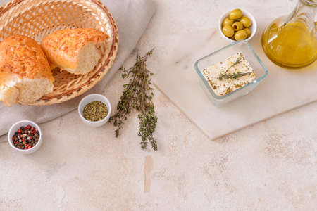 Tasty feta cheese with herbs, oil and bread on white backgroundの写真素材