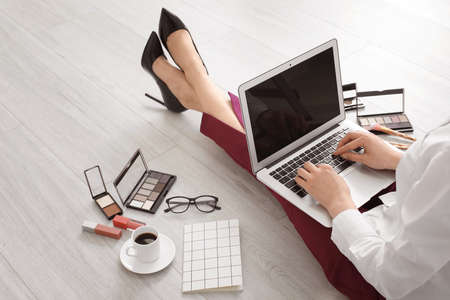 Female makeup artist with laptop and cosmetics at homeの写真素材