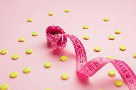 Measuring tape and weight loss pills on color backgroundの写真素材