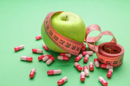 Measuring tape, apple and weight loss pills on color backgroundの写真素材