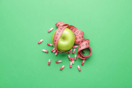 Measuring tape, apple and weight loss pills on color backgroundの写真素材