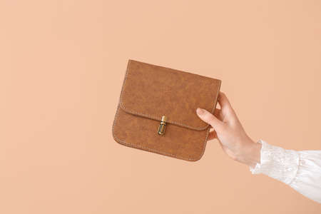 Hand of beautiful woman with stylish bag on color backgroundの写真素材