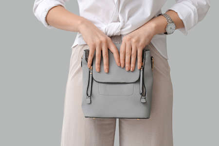 Beautiful woman with stylish bag on gray backgroundの写真素材