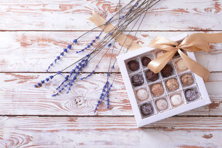 Box with delicious candies on white wooden backgroundの写真素材