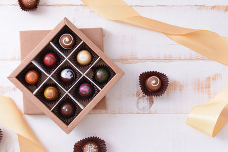Box with delicious candies on white wooden backgroundの写真素材