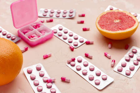Box with weight loss pills and grapefruit on color backgroundの写真素材