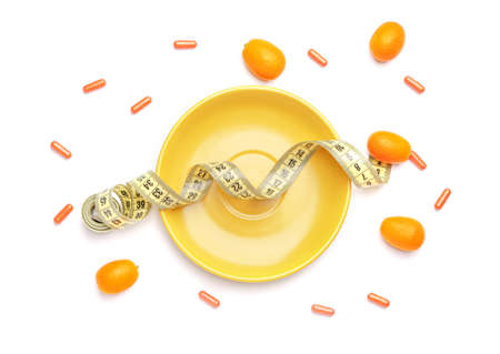 Plate with weight loss pills and measuring tape on white backgroundの写真素材