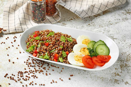 Plate with tasty buckwheat, eggs and vegetables on tableの写真素材