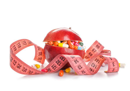 Apple with weight loss pills and measuring tape on white backgroundの写真素材