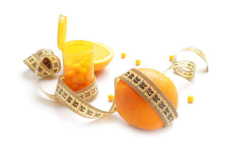 Bottle with weight loss pills, orange fruit and measuring tape on white backgroundの写真素材