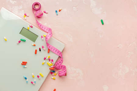 Weight loss pills, scales and measuring tape on color backgroundの写真素材