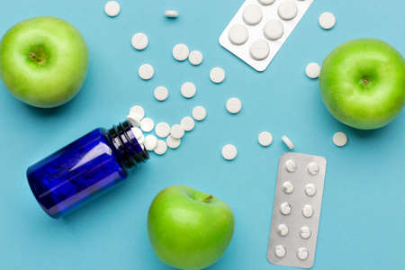Bottle with weight loss pills and apples on color backgroundの写真素材