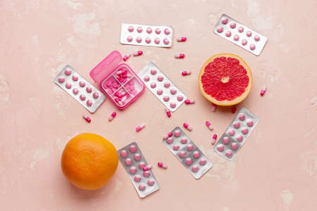 Box with weight loss pills and grapefruit on color backgroundの写真素材