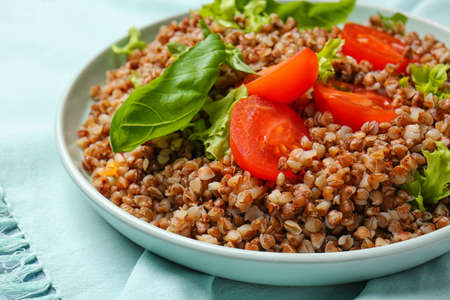 Plate with tasty buckwheat porridge and vegetables on table, closeupの写真素材
