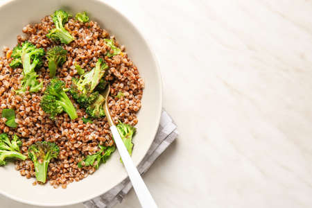 Bowl of tasty buckwheat porridge and broccoli on tableの写真素材