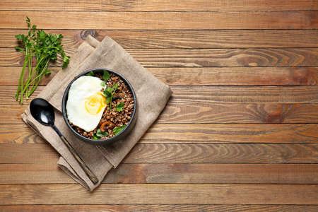 Bowl of tasty buckwheat porridge and egg on tableの写真素材