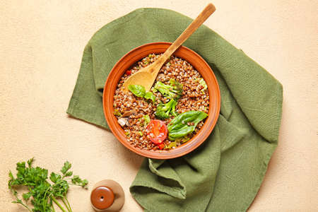 Bowl of tasty buckwheat porridge and vegetables on color backgroundの写真素材