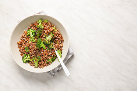 Bowl of tasty buckwheat porridge and broccoli on tableの写真素材
