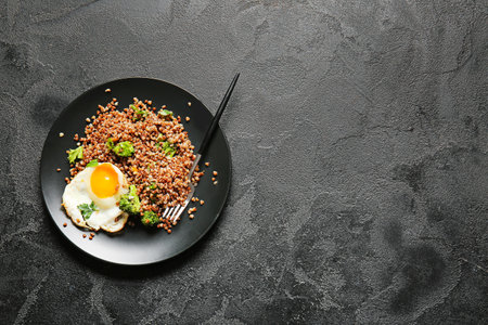 Plate with tasty buckwheat porridge, egg and broccoli on dark backgroundの写真素材