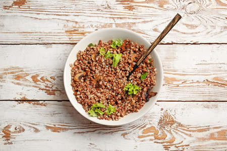 Plate with tasty buckwheat porridge and mushrooms on tableの写真素材