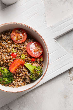Bowl of tasty buckwheat porridge and vegetables on tableの写真素材