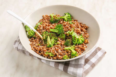 Bowl of tasty buckwheat porridge and broccoli on tableの写真素材