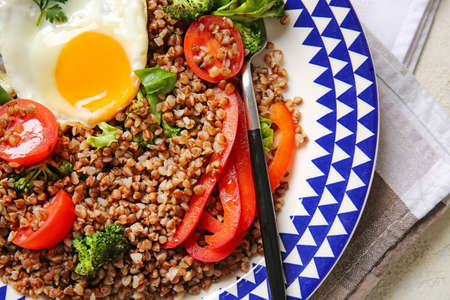 Plate with tasty buckwheat porridge, egg and vegetables on table, closeupの写真素材