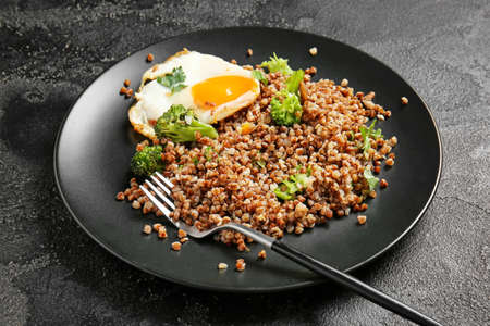 Plate with tasty buckwheat porridge, egg and broccoli on dark backgroundの写真素材