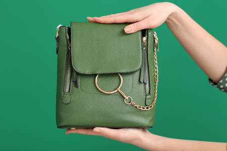Female hands with stylish bag on color backgroundの写真素材