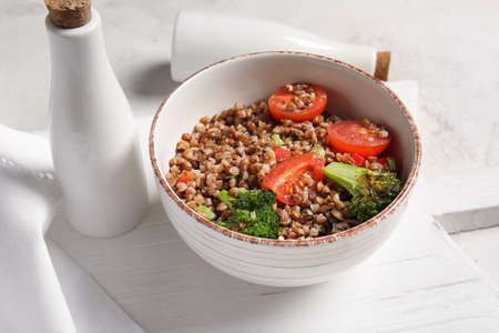 Bowl of tasty buckwheat porridge and vegetables on tableの写真素材