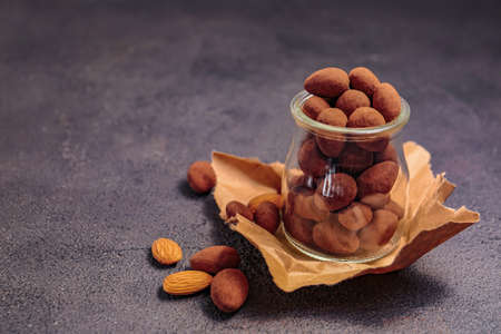Jar with tasty chocolate nuts on dark backgroundの写真素材