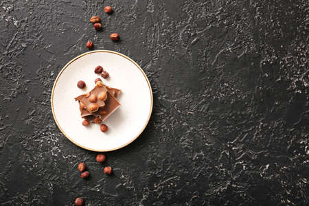 Plate with tasty chocolate and hazelnuts on dark backgroundの写真素材