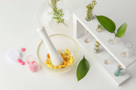 Plant based pills with mortar and test tubes on white backgroundの写真素材