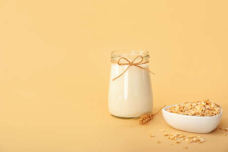 Jar of tasty oat milk on color backgroundの写真素材