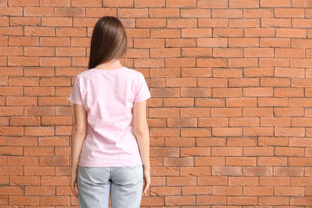 Young woman in stylish t-shirt on brick backgroundの写真素材