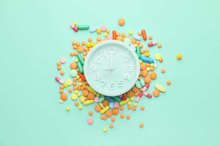 Alarm clock with different pills on color backgroundの写真素材