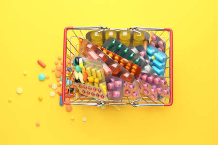 Small shopping basket with pills on color backgroundの写真素材