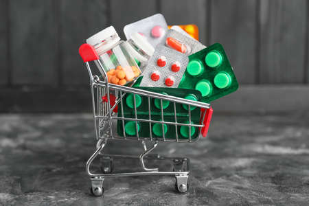 Small shopping cart with pills on dark backgroundの写真素材