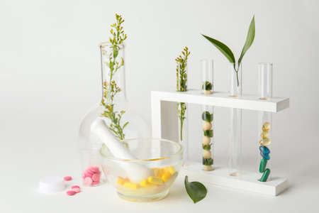 Plant based pills with mortar and test tubes on white backgroundの写真素材
